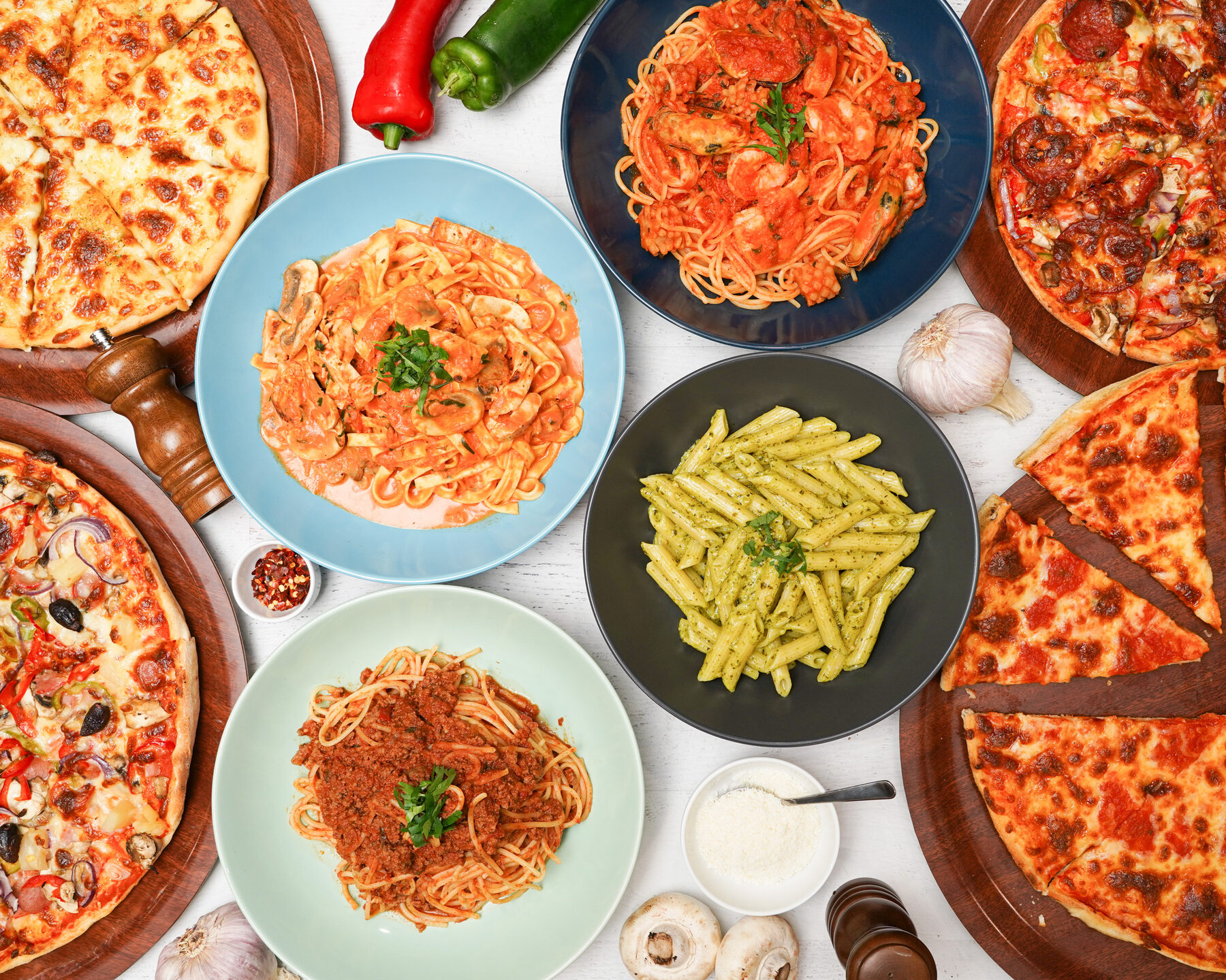 A spread of Sam's Italian pizzas and pastas on a rustic wooden table