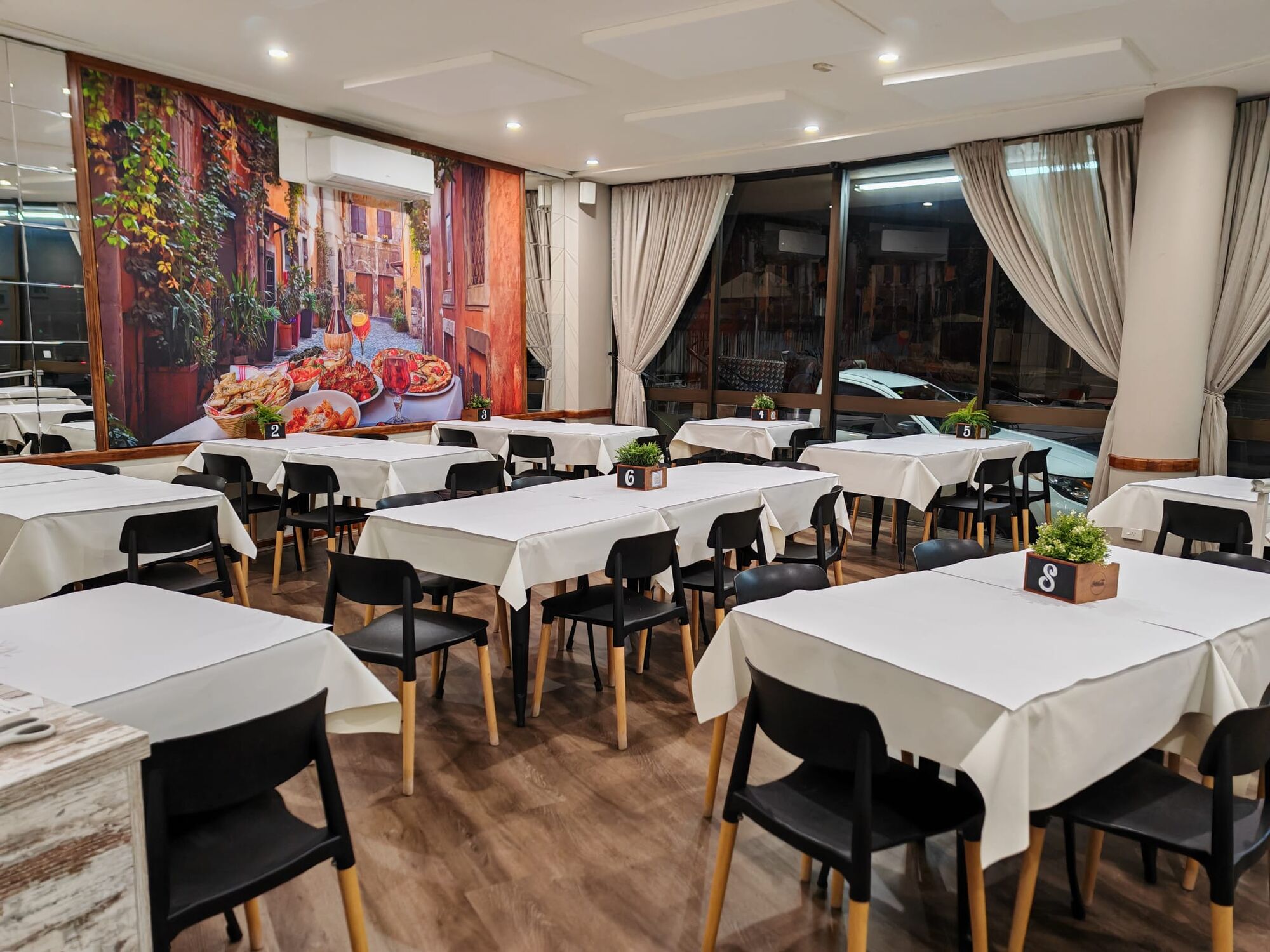 Sam's Italian Restaurant dining room with a Roman streetscape mural and set tables