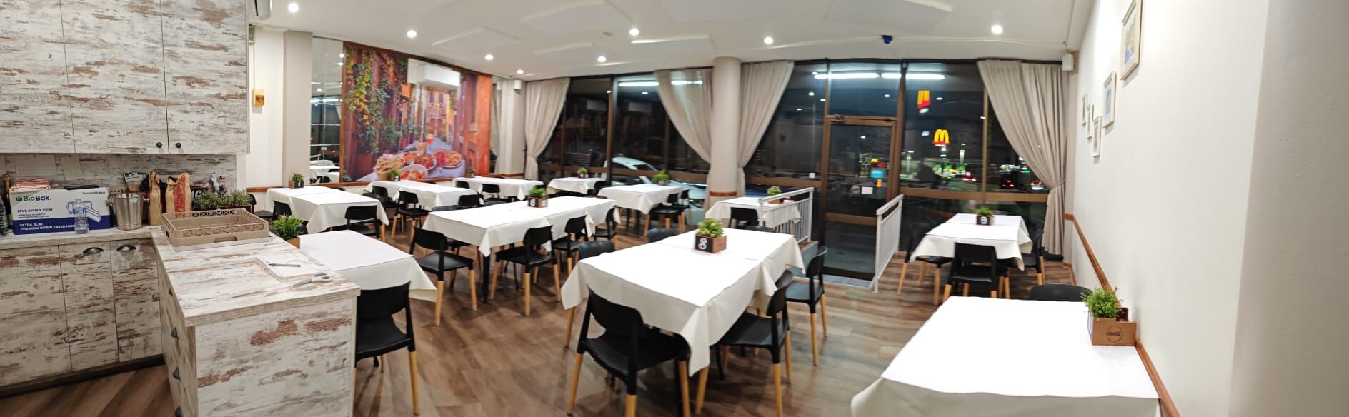 Sam's Italian Restaurant dining room set for service, with a Roman streetscape mural